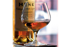 a full brandy glass in the foreground along with a bottle of brandy in the background