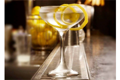 a tall cocktail glass filled with lemon cocktail, decorated with lemon peel 