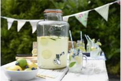 glass drinks dispenser on picnic table containing home made lemonade