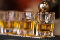three full glass shot glasses placed on a bar matt