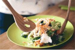 salad spoons placing salad onto a plate