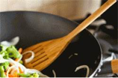 wooden turner being used to flip vegetables in a pan 