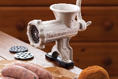 meat mincer clipped to a table top alongside sausages 