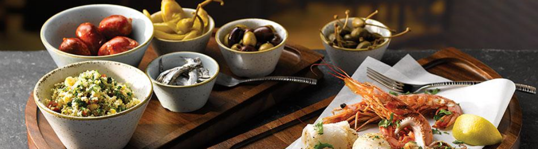 different sized bowls filled with a variety of food served on wooden serving boards 