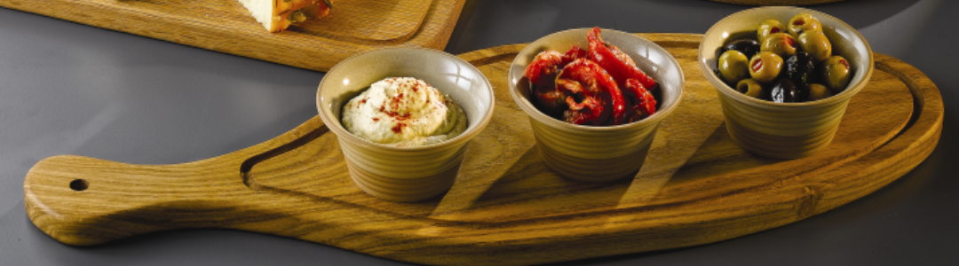 three ramekins filled with a variety of foods on an oval wooden serving board