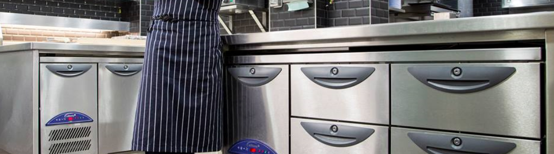 chef standing beside refigerated counters in a kitchen