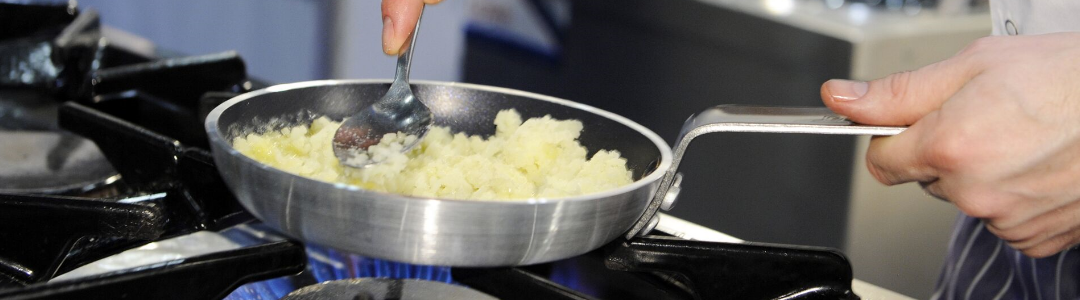 Chef cooking with frypan on gas stove