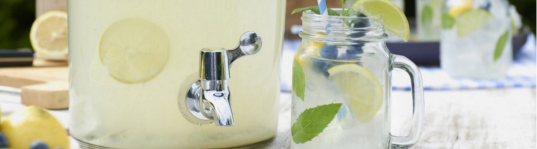 glass drinks dispenser on picnic table containing home made lemonade