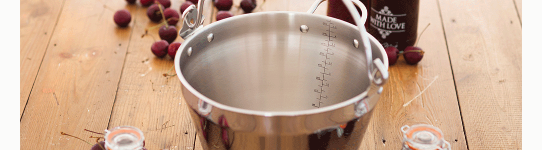 stainless steel measuring jug with berries in the background 