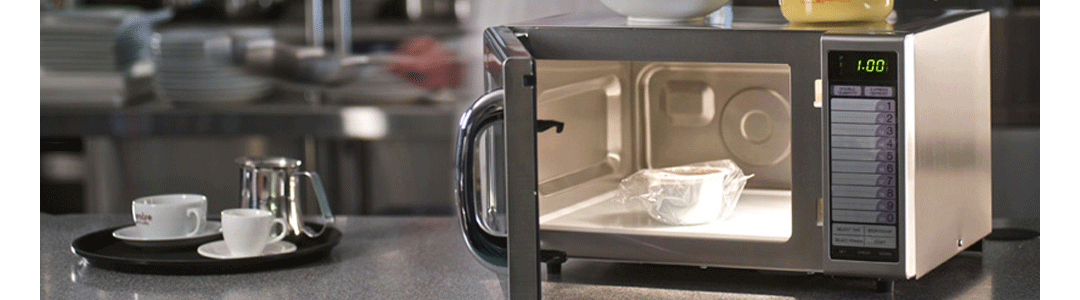 microwave on kitchen work surface, tray with two cups and teapot on