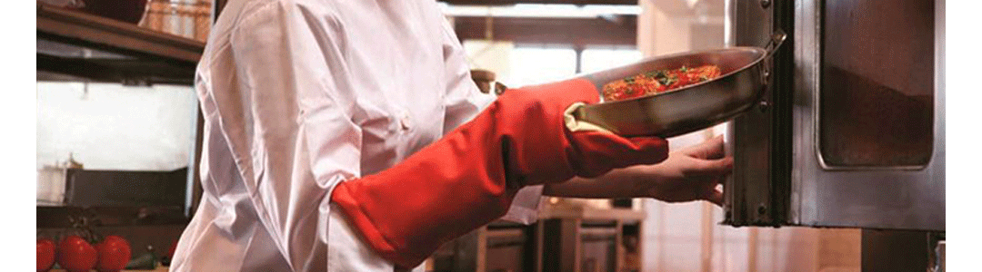 chef wearing oven gloves putting pan into oven 