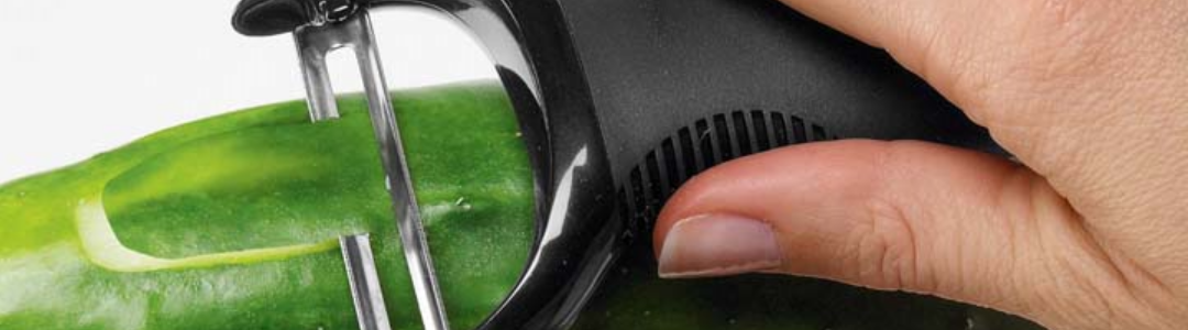 a hand holding a peeler peeling a cucumber