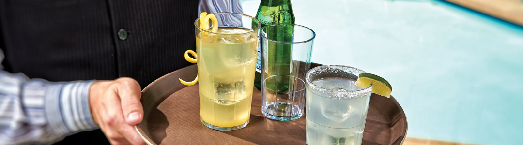 waiter carrying tray of plastic glasses by pool