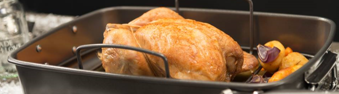 roast chicken being cooked in a roasting pan 