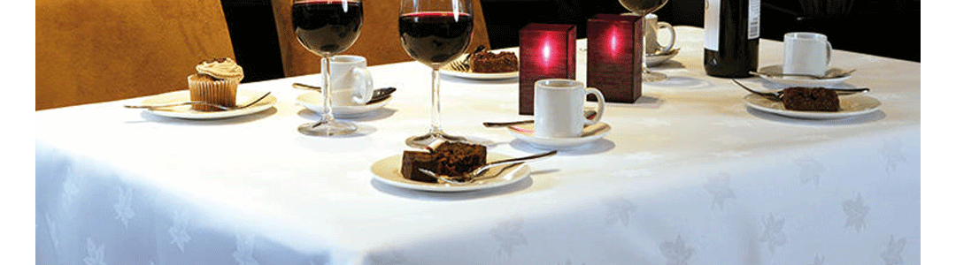 white patterned table linen on a set dinner table 