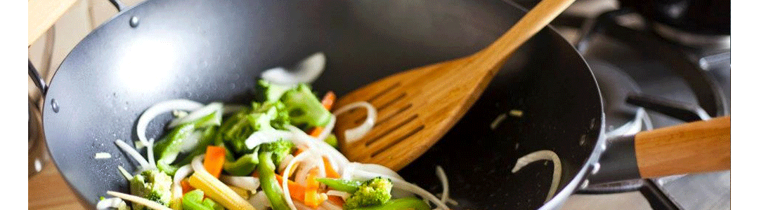 wooden turner being used to flip vegetables in a pan 