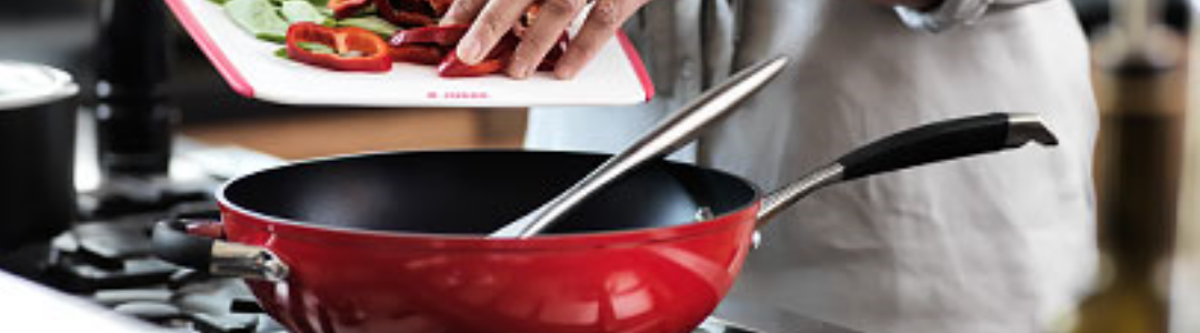 ingredients being tipped in to a red non stick wok on stove 